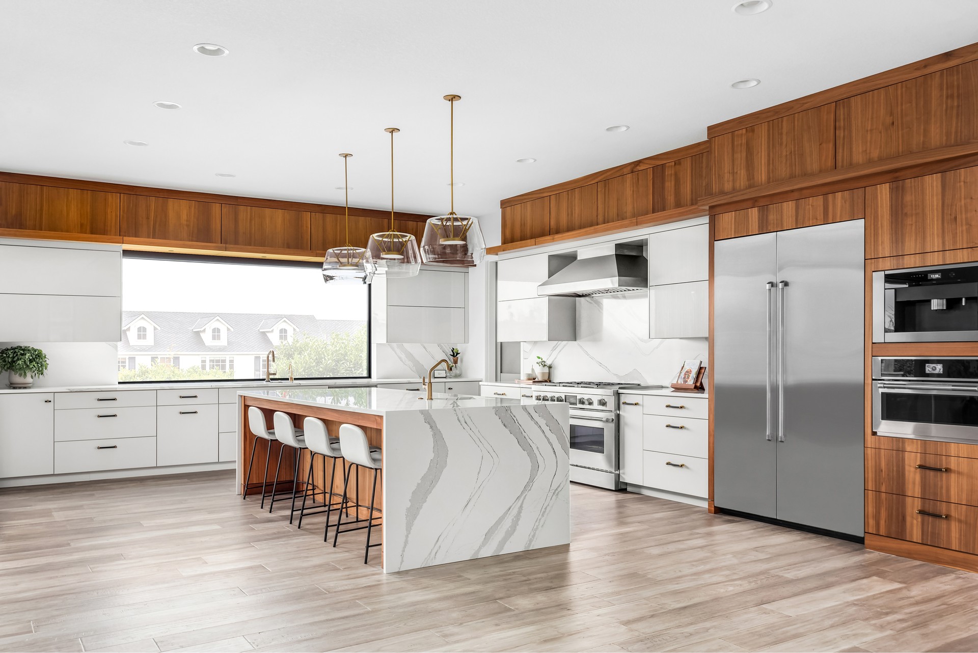 Beautiful kitchen in new luxury home with waterfall quartz island, pendant lights and hardwood floors.